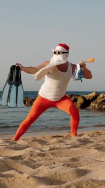 Noel Baba yaz tatili. Noel Baba, eğleniyor. Noel Baba yoga yapıyor. Komik Noel Baba, güneş gözlüklü, yüzgeçli ve şnorkelli, deniz kenarında. Noel Baba şnorkelle dalacak
