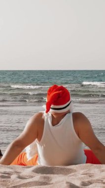 Noel Baba yaz tatili. Noel Baba eğleniyor. Komik Noel Baba, yüzgeçli, deniz kenarında kumlu sahilde otururken dinleniyor. arka plan.