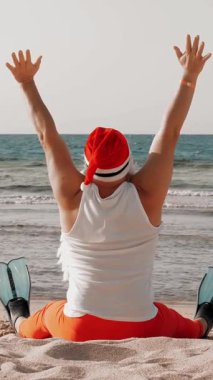 Noel Baba yaz tatili. Noel Baba eğleniyor. Komik Noel Baba, yüzgeçli, deniz kenarında kumlu sahilde otururken dinleniyor. arka plan.