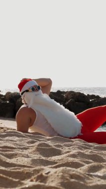 Noel Baba yaz tatili. Noel Baba eğleniyor. Komik Noel Baba, paletlerle, deniz kenarında kumlu sahilde uzanırken dinleniyor..