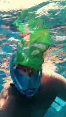 Denizde ya da okyanusta çöp toplama. Adam, şnorkel maskesi takıyor, yüzüyor ve suya atılmış çöpleri topluyor. Yakın plan. Deniz, okyanus kirliliği. çevre koruması,