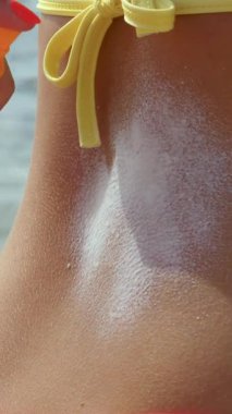 Güneş kremi. Güvenli bronzlaşma. Güneş yanığı. Zararlı güneş radyasyonuna karşı koruma. Yakın plan. Kadın eli vücut derisine güneş kremi sürer. Sahilde, denizde. Güneşli sıcak bir gün