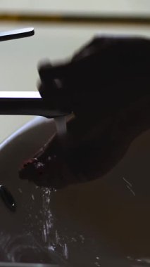 El yıkama. Yakın plan. Kadın eli silueti. Kadın ellerini musluktan akan suyun altında yıkıyor..