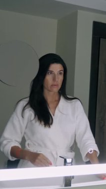 Işığı aç ya da kapat. Yakın plan. Bir kadının eli, parlak kırmızı manikürlü, ışığı kapatır, aynadaki arka ışığı.