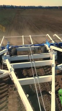 Çiftçinin taksisinden çiftliğin verimli tarlasına bakın. Traktör saban sürüyor, toprağı büyük metal bir sabanla donatıyor, tarıma elverişli topraklarda çok toz kaldırıyor, toprağı ekime hazırlıyor. Bahar ekini