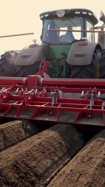 UKRAINE, CHERKASY, 5 Mayıs 2019: yakın plan, mekanize makine patates ekimi süreci. Özel ekipmanlı büyük traktör, uzun düz üst sıraları, çizgileri, tepecikleri, yeni ekilmiş patatesleri, ekilmiş siyah toprak tarlasında, ekim mevsiminde