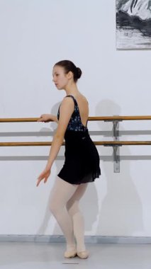 Profil görüntüsündeki dansçı, bale hareketini kollarını uzatarak ve uygun bale duruşuyla yapıyor..