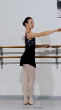 Temel engelleme egzersizleri yaparken zarif bir kavisle kolunu uzatan bale öğrencisi.