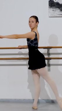 Dansçı, bar egzersizi sırasında uygun hizayı sürdürüyor, klasik bale tekniğini ve biçimini gösteriyor.