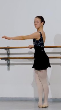 Siyah taytlı ve beyaz taytlı balerin, Barre 'de duruş çalışması yapıyor, birinci sırada duruyor..