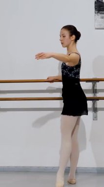 Barre 'de çalışırken kolunu uzatan bale öğrencisi, bale pozisyonunun temellerini gösteriyor..