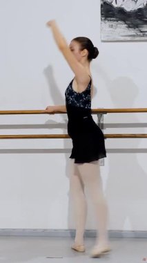 Profil görüntüsündeki dansçı, bale hareketini kollarını uzatarak ve uygun bale duruşuyla yapıyor..