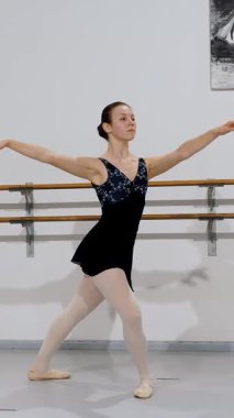 Günlük alıştırma sırasında klasik bale formunu sergileyen dönüşmüş pozisyondaki bir balerin..