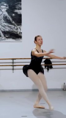 Temel engelleme egzersizleri yaparken zarif bir kavisle kolunu uzatan bale öğrencisi.