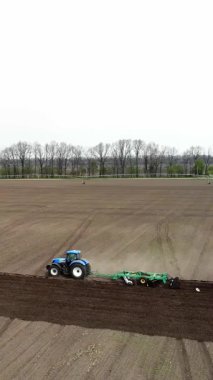 Havacılık. Bahar güneşli bir gün. Tarımsal bir tarlada traktör toprak, toprak ve modern tarım sürüyor. Eko çiftliği.