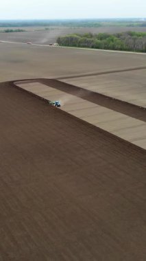 Havacılık. Bahar güneşli bir gün. Tarımsal bir tarlada traktör toprak ve toprak sürüyor. Çiftliklerde otomatik patates ekimi. Modern tarım. Eko çiftliği.