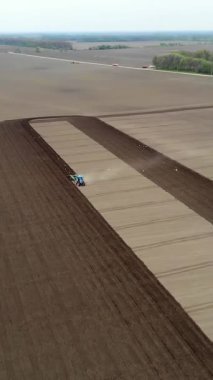 Havacılık. Bahar güneşli bir gün. Tarımsal bir tarlada traktör toprak ve toprak sürüyor. Çiftliklerde otomatik patates ekimi. Modern tarım. Eko çiftliği.