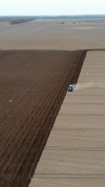 Havacılık. Bahar güneşli bir gün. Tarımsal bir tarlada traktör toprak ve toprak sürüyor. Çiftliklerde otomatik patates ekimi. Modern tarım. Eko çiftliği.