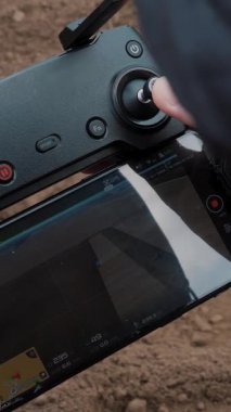 Yakın plan, erkek dronu kontrol eder, traktörün tarlada nasıl çalıştığını videoya çeker. Tarımsal olarak patates yetiştirme, ekme. yeni tarım teknolojisi ve yenilik