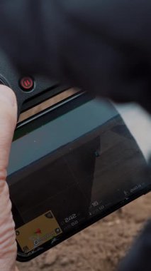 Yakın plan, erkek dronu kontrol eder, traktörün tarlada nasıl çalıştığını videoya çeker. Tarımsal olarak patates yetiştirme, ekme. yeni tarım teknolojisi ve yenilik