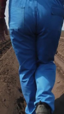 Çiftçi, tarımcı tarladaki toprak sıraları arasında, tabletle, ekicinin patates ekme kalitesini test ederek derin bir çizgide yürüyor. Modern tarım. Bahar güneşli gün.