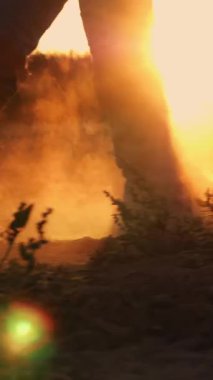 Çizmeli çiftçi tarlada yürüyor. Yakın plan. Çiftçilik botları içinde bacaklar. Tozlu, toprak. Gün batımında arka ışıklandırma. Taze sürülmüş tarım arazisi. Alt görünüm