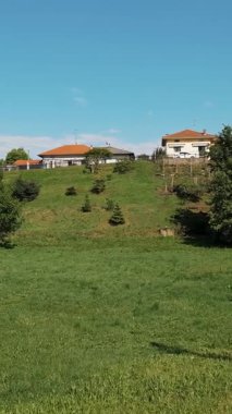 Kırsal evleri kırmızı kiremitli çatılar ve açık mavi gökyüzünün altında kozalaklı ağaçlar altında yeşil vadi.