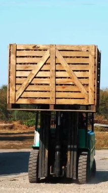 Elma hasatı Forklift kamyonu yeni toplanmış elmalarla dolu ahşap sandıklarla dolu açık havada boşaltıyor. Yükleyici depolama için elma kutularını depoya aktarır.