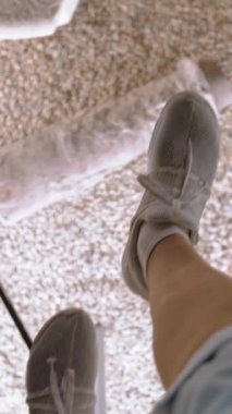 İlk bakış açısı. Cam altında arkeolojik kazılar müzesi. Tarihi eserler. Sağlam bir cam yüzeyde yürüyen bir turistin ayaklarının en üst görüntüsü..