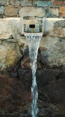 Bir dağ pınarı. Hayvanlar için içme suyu. Taş bir şelale. Dağ pınarından suyla dolu bir çukur. İçilebilir suyu olan metal bir çeşme. Yüksek kalite 4k görüntü