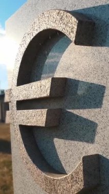 Gri granitten oyulmuş taş para birimi sembolü. Gün ışığında açık gölgeler. Euro sembolü.