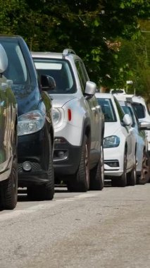 Park yeri. Park halindeki arabalar güneşli bir günde yol kenarında dizilir..