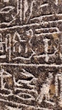 Taşa oyulmuş eski Mısır hiyeroglifleri. Dini veya tarihi metni, derin ve detaylı oymalarla temsil eden yatay sembol satırları.