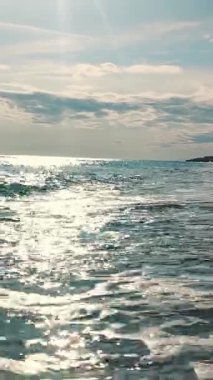 Okyanus sakin ve güneş suyun üzerinde parlıyor. Kumsal boş ve gökyüzü temiz.