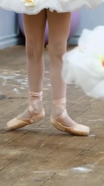 closeup , Bale ayakkabıları genç balerin bacaklar, sivri, bej mayolar, beyaz tutu etek, barre yakın egzersizleri gerçekleştirmek, bir bale okulunda eski bir ahşap zemin üzerinde, bale dersi sırasında