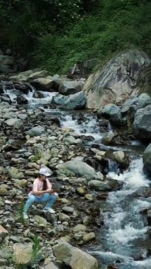 Ormanda bir nehrin fotoğrafını çeken bir kız. Alplerdeki dağ nehri.