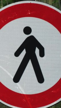 Yol tabelası, yuvarlak, ortasında siyah siluet olan bir adam ve kırmızı çerçeveli, yaya trafiğini engelleyen. Yakın plan. Arka planda, onarım çalışmaları yolda devam ediyor. Alp dağlarında büyük bir köprü. yaz günü.
