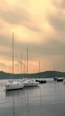 BELLA, İtalya, 11 Haziran 2023: Dağlarda göl. Birçok küçük yelkenli yat ve yelkenli göl kıyısına demirlemiştir. Gün batımı. Dağ arkaplanı. Sinematik çerçeve. Romantik atmosfer. Sakin ve huzur verici bir sahne. Yeşil gezegen.