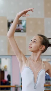 Bale salonunda, beyaz bale etekli kız, bale yapıyor, sütyen bölümünün provasını yapıyor, zarif bir şekilde elini kaldırıyor ve indiriyor, koridordaki korkuluklarda duran genç balerin...