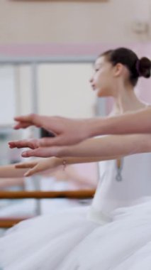 Bale salonunda genç balerinler allonge, eller zarif yukarı ve aşağı, yakın çekim hareket gerçekleştirmek.