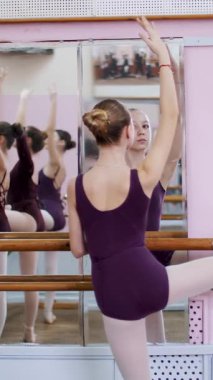 Bale salonundaki korkulukta duran kız. Genç balerin stüdyoda bale barını kullanarak esniyor. Mor taytlı genç balerin...