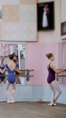 Bale salonunda, mor taytlı genç balerinler dans eder, dans eder, parmak uçlarında bale salonundaki parmaklıklar üzerinde dururlar..