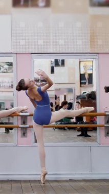 Bale salonunda mor tayt içinde genç balerinler bölümü de sutyen eğimli gerçekleştirmek, viraj geri, geri, Korkuluk Hall, zarif yukarı ve aşağı, ayakta eller hareket yatır..