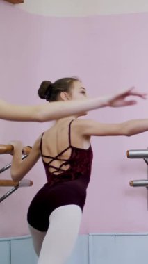 Bale salonunda genç balerinler mor tayt içinde bölümü de sutyen germe ile gerçekleştirmek, mekik genişletilmiş bir bacak ile geri, zarif eller taşıyarak, Korkuluk salonda ayakta..