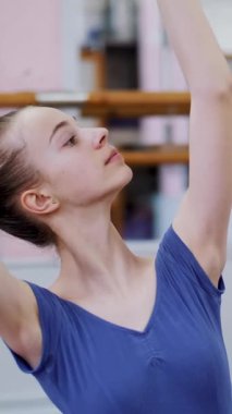 dans salonu, mor tayt içinde genç balerin bölümü de sütyen 3 pozisyon ileri tilt ile gerçekleştirir, kız üzerinde sicim, zarif, ellerini hareket yakın çekim oturuyor.