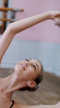 dans salonu, mor tayt içinde genç balerin bölümü de sütyen 3 pozisyon ileri tilt ile gerçekleştirir, kız üzerinde sicim, zarif, ellerini hareket yakın çekim oturuyor.