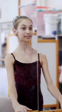 dans salonu, mor tek parça streç giysi içinde genç balerin developpe bir kenara pointe ayakkabılarla gerçekleştirir, bacağını zarif, ayakta barre adlı bale sınıf aynada yakınındaki yukarı yükseltir. yakın çekim.