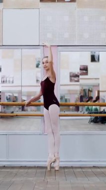 dans salonu, mor tayt içinde genç balerinler grand battement geri pointe ayakkabılarla gerçekleştirmek, bacakları zarif, ayakta barre adlı bale sınıf aynada yakınındaki yukarı yükseltmek..