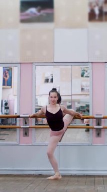 Dans salonunda, siyah taytlı genç balerinler barlarda zarifçe esniyorlar, bale sınıfında aynanın önünde aynanın önünde duruyorlar...