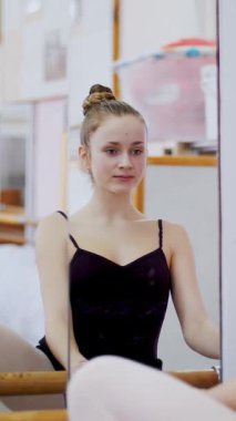 dans salonu, genç balerin siyah tek parça streç giysi içinde belirli bir bale egzersiz, barre, zarif, barre adlı bale sınıf aynada yakın duran gerçekleştirir..